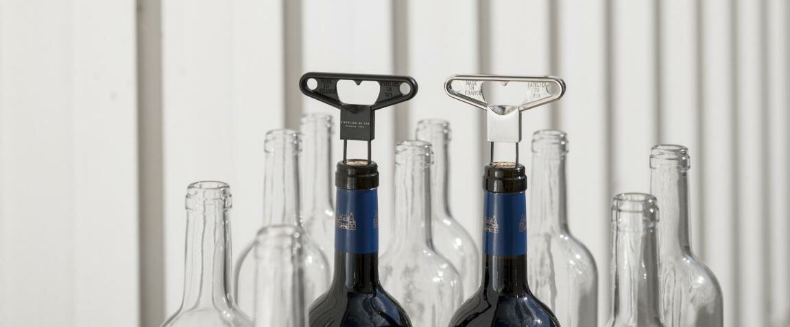 Two double-bladed corkscrews on wine bottle