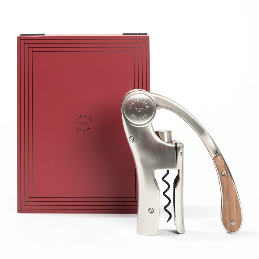 Lever corkscrew next to its red wooden case