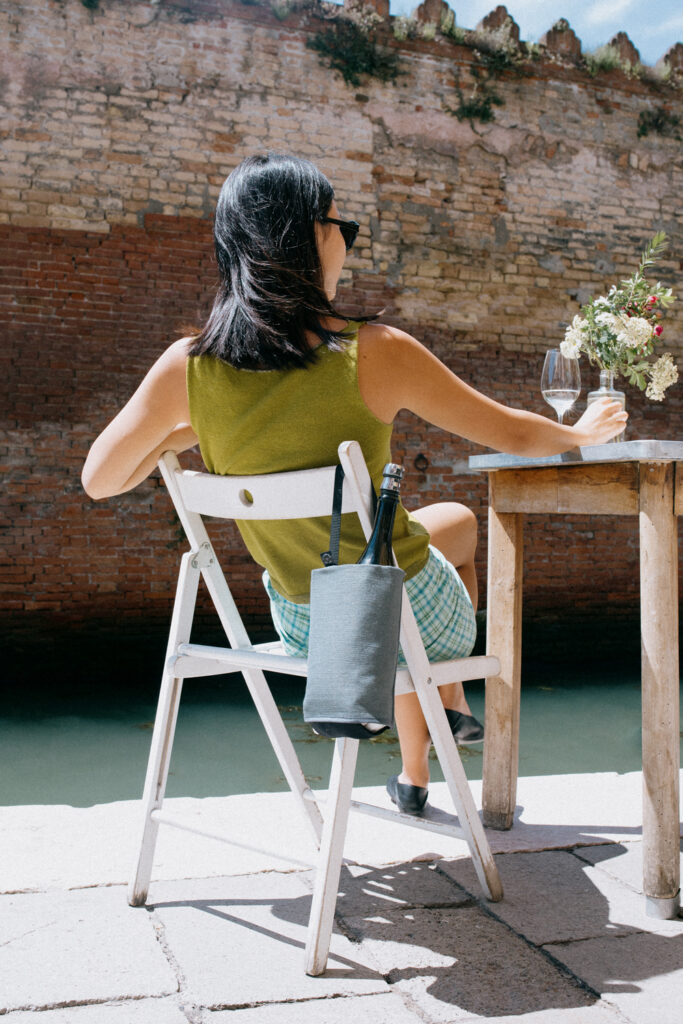 Grey linen wine cooler and bottle holder hanging on a chair